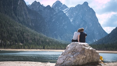 一对夫妇坐在一块石头上望着湖
